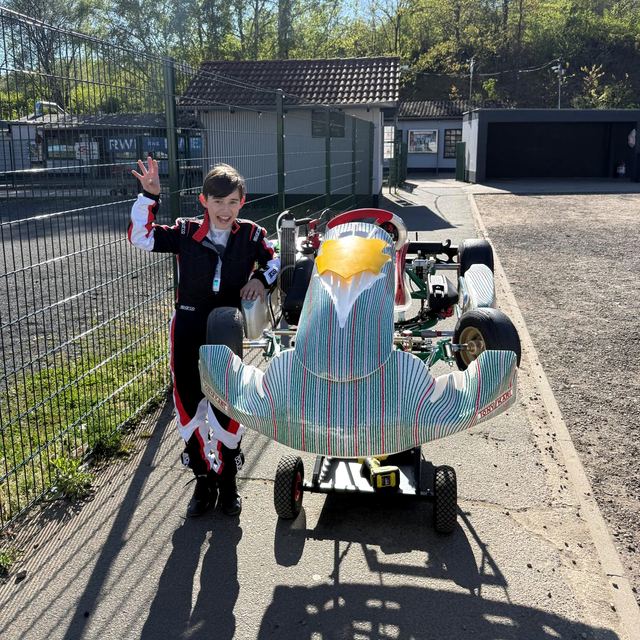 Maximilian winkt neben seinem Tony Kart an der Strecke